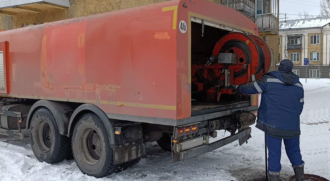 Каналопромывочная машина и работник прочищают засор в канализационной системе в Донецке